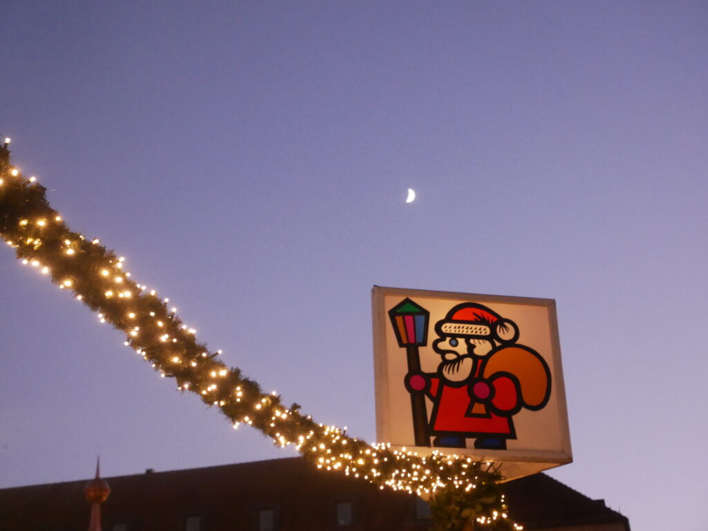 ニュルンベルクのクリスマスマーケット。サンタクロースが描かれた看板。背後に三日月が浮かんでいる。